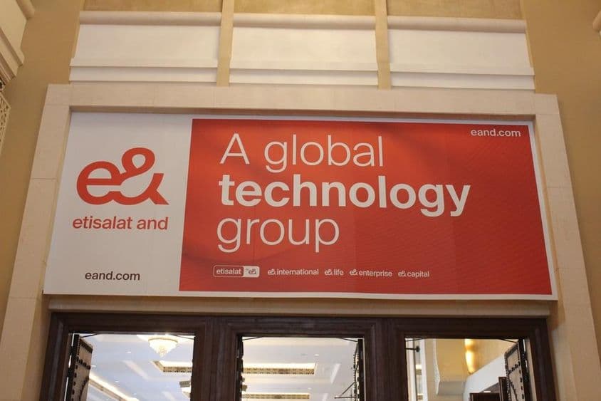 ग्लास प्रवेश द्वार के साथ एक स्टोरफ़्रंट के ऊपर एतिसलात कंपनी का विज्ञापन।