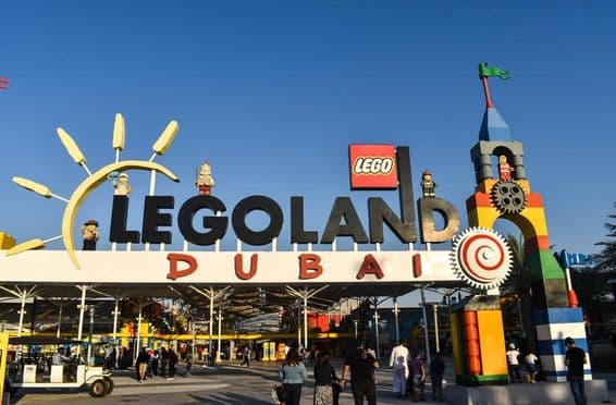 LEGOLAND दुबई का प्रवेश द्वार, लोगों और सामने गॉल्फ गाड़ी के साथ।