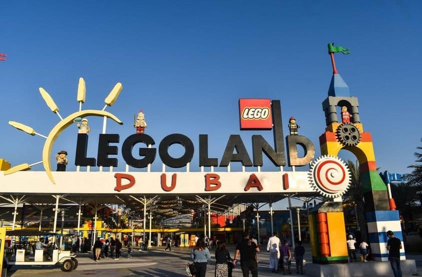 LEGOLAND दुबई का प्रवेश द्वार, लोगों और सामने गॉल्फ गाड़ी के साथ।