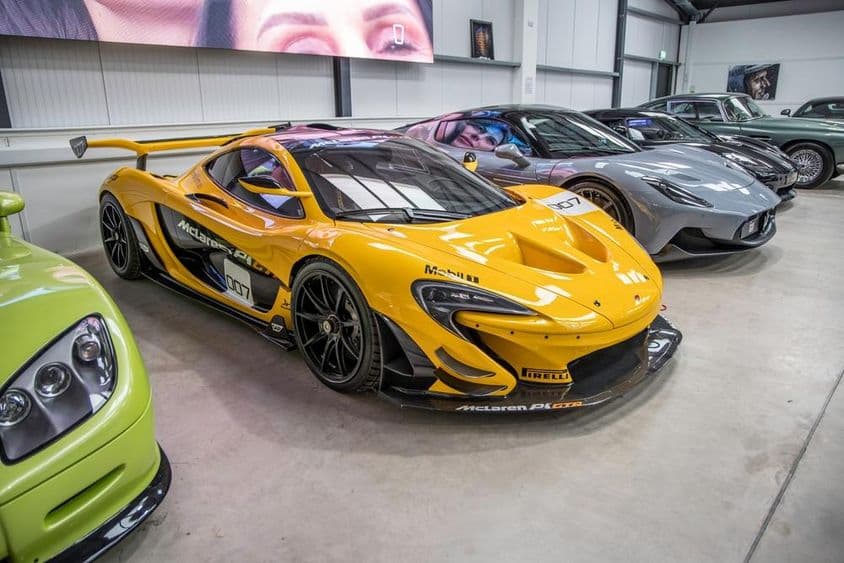 McLaren और अन्य कारें गेराज में खड़ी हैं।