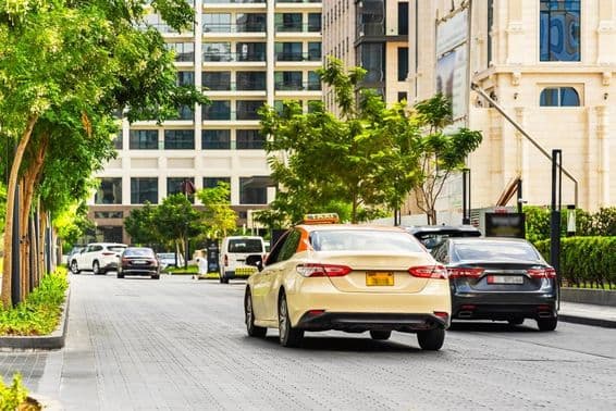 दुबई की सड़क पर कारें, अग्रभूमि में टैक्सी, पीछे घर।