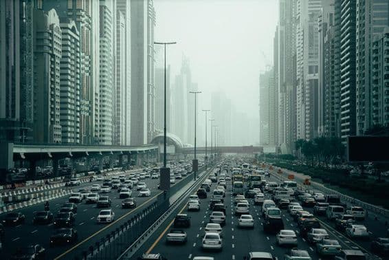 दुबई के शहर में भीड़भाड़ वाला हाईवे, 2x7 लेन, दोनों तरफ गगनचुंबी इमारतें।