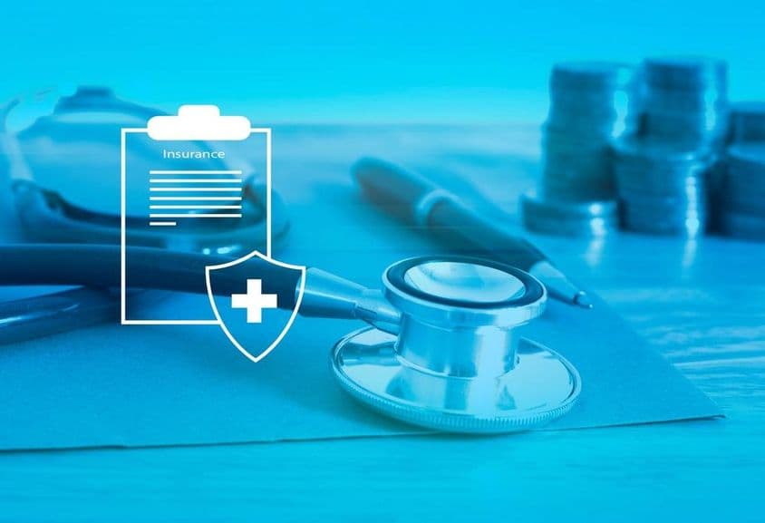 स्वास्थ्य बीमा अग्रभूमि, पृष्ठभूमि में स्टेथोस्कोप और छोटे सिक्के।