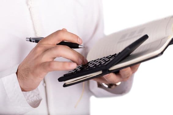 हाथ से नोटपैड पर कैलकुलेटर का संचालन किया जा रहा है।