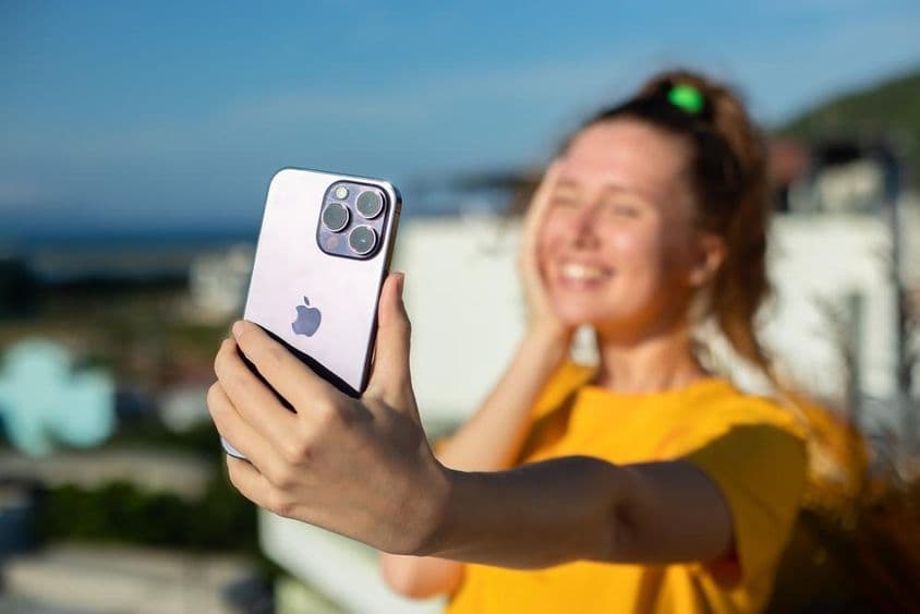 एक युवा लड़की आईफोन फोन पकड़े हुए।