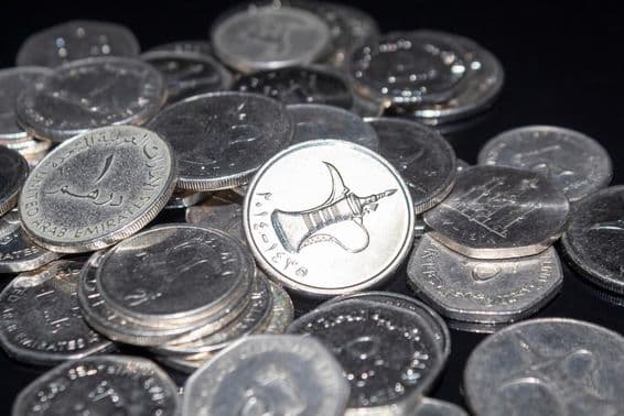 कुछ 1 दिरहम के सिक्के चारों ओर बिखरे हुए हैं।