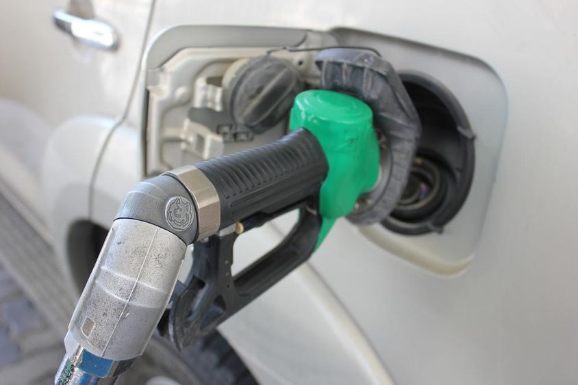 एक सफेद कार में एक गैस स्टेशेन पर ईंधन भरते हुये।