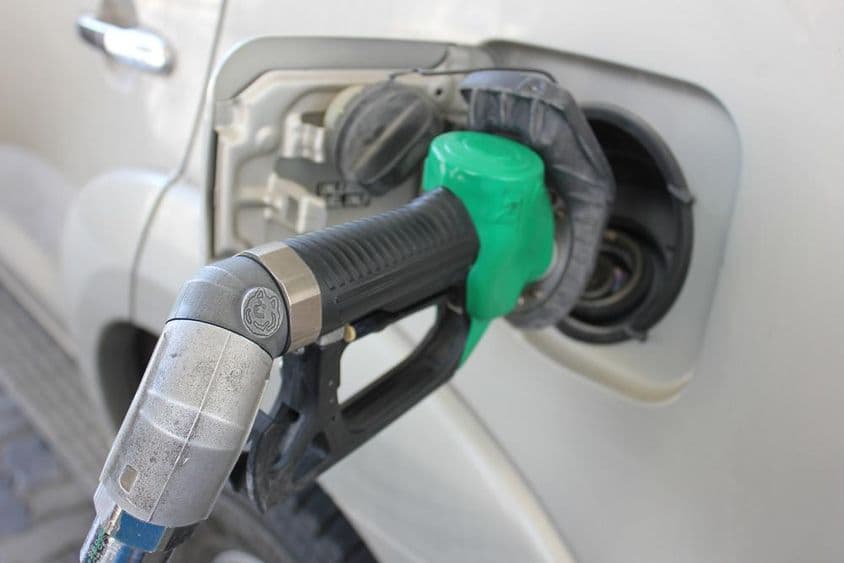 एक सफेद कार में एक गैस स्टेशेन पर ईंधन भरते हुये।