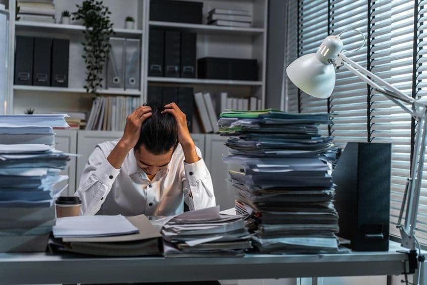 काम की अत्यधिकता के चलते सिर पकड़ने वाला कार्यालय कर्मचारी।