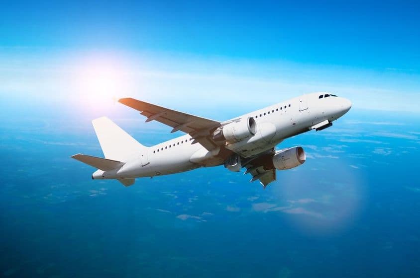 आकाश में उड़ता सफेद विमान।