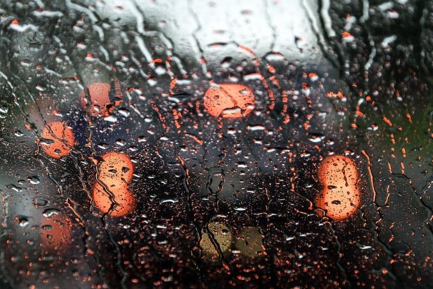 एक गीली कार की खिड़की के माध्यम से दुबई का दृश्य।