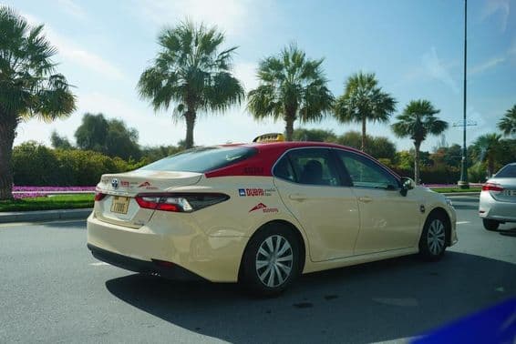 सड़क पर चलती लाल छत वाली दुबई टैक्सी।