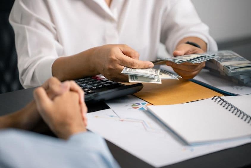 एक व्यक्ति समझदारी से वित्त प्रबंधन कर रहा है, अपनी सैलरी से नकदी बचा रहा है, भविष्य के भुगतान और व्यवसाय निवेश के लिए स्थिर आय सुनिश्चित कर रहा है।