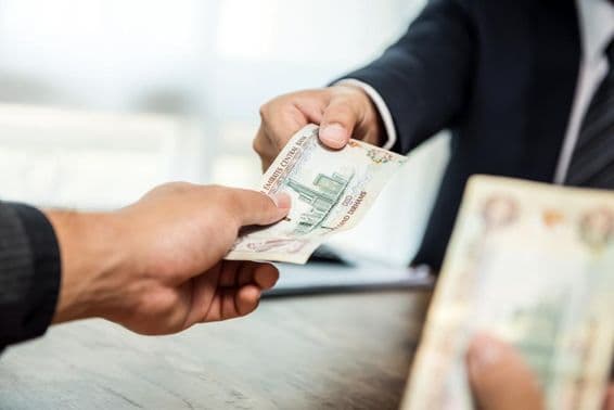 व्यवसायी एक साथी को यूएई दिरहम मुद्रा में पैसा सौंपते हुए।