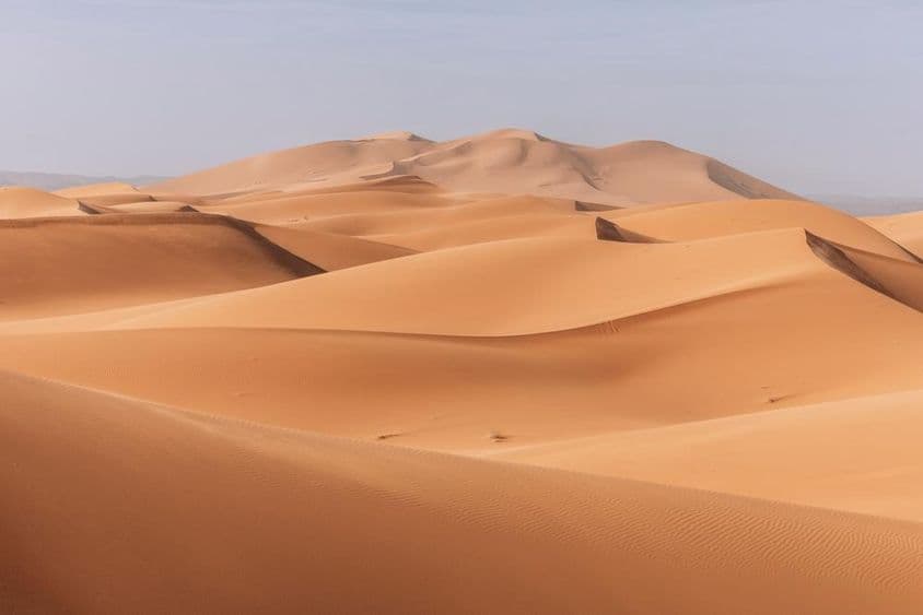 ऊँचे टीले, सुनहरी सूर्यास्त के समय एक शांत, शांत परिदृश्य।