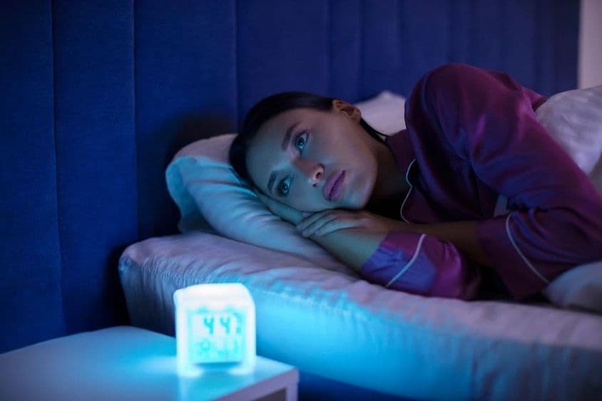 अवसादग्रस्त नींदहीन महिला बिस्तर पर लेटी हुई, दूर देखती हुई, नींद आने में असमर्थ, अनिद्रा से पीड़ित।