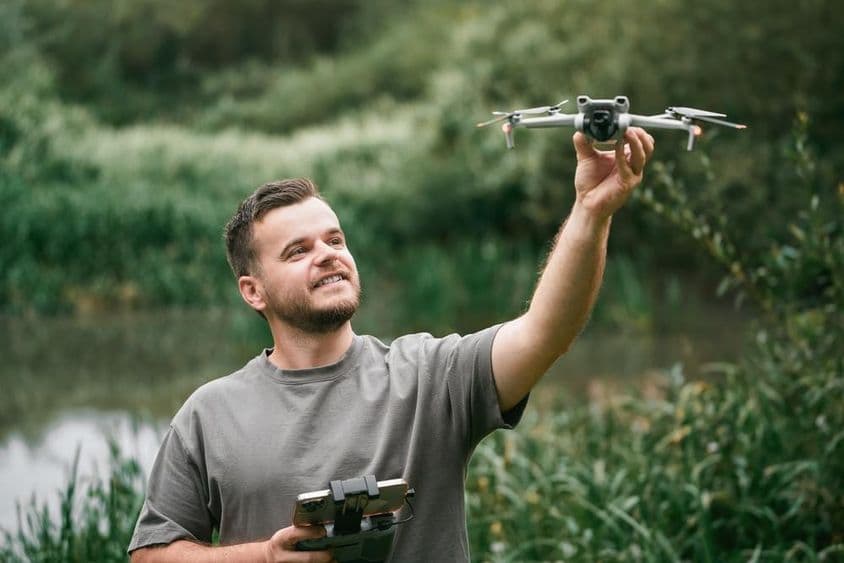 बाहर की कक्षा में ड्रोन हाथ में लिए ड्रोन प्रशिक्षक।