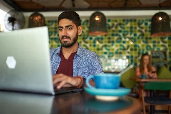 एक भारतीय व्यक्ति एक ट्रेंडी कोवर्किंग स्पेस में काम करता हुआ।
