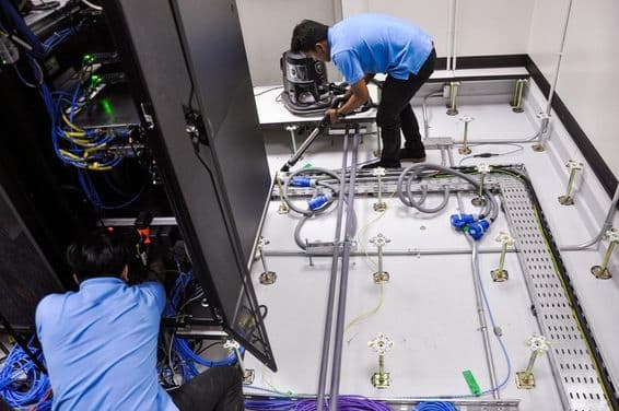 सर्वर रूम बनाते हुए वर्कर्स, उठी हुई फर्श और रैक केबिनेट्स।