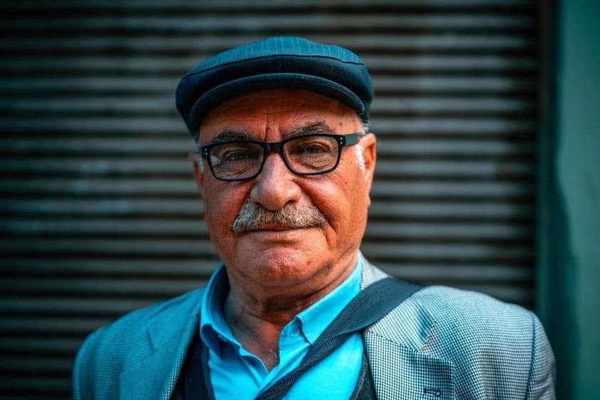 सड़क पर टोपी पहने हुए एक बृद्ध व्यक्ति।