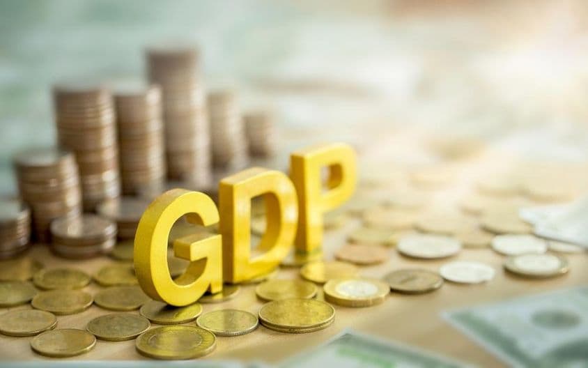 GDP शिलालेख, पृष्ठभूमि में सिक्कों का ढेर।