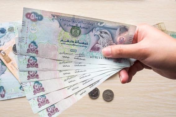 एक लड़की के हाथ में 500 यूएई दिरहम के नोट, कागजी मुद्रा।