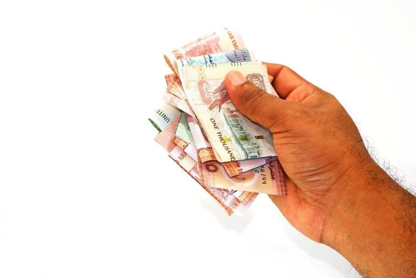 एक आदमी के हाथ में दिरहम बैंकनोट्स।