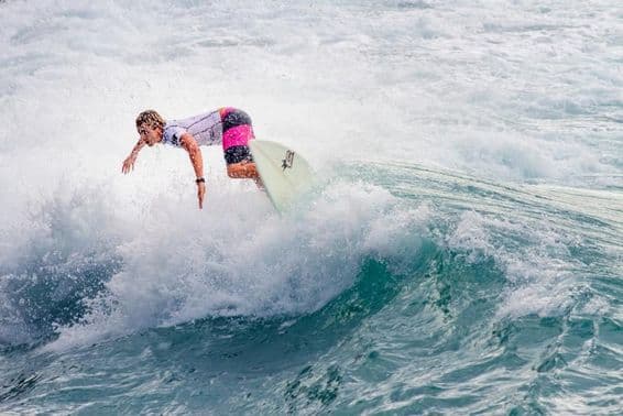 एक युवा लड़का बड़ी वेव सर्फ करते हुए।