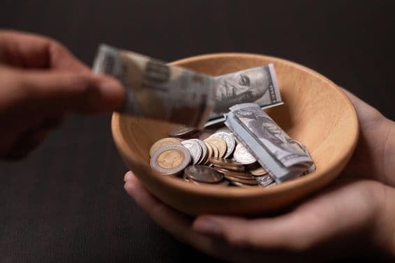 लकड़ी के बर्तन में एकत्रित किया जा रहा दान।