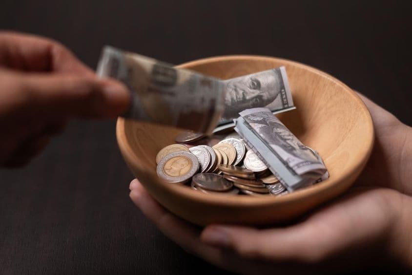 लकड़ी के बर्तन में एकत्रित किया जा रहा दान।