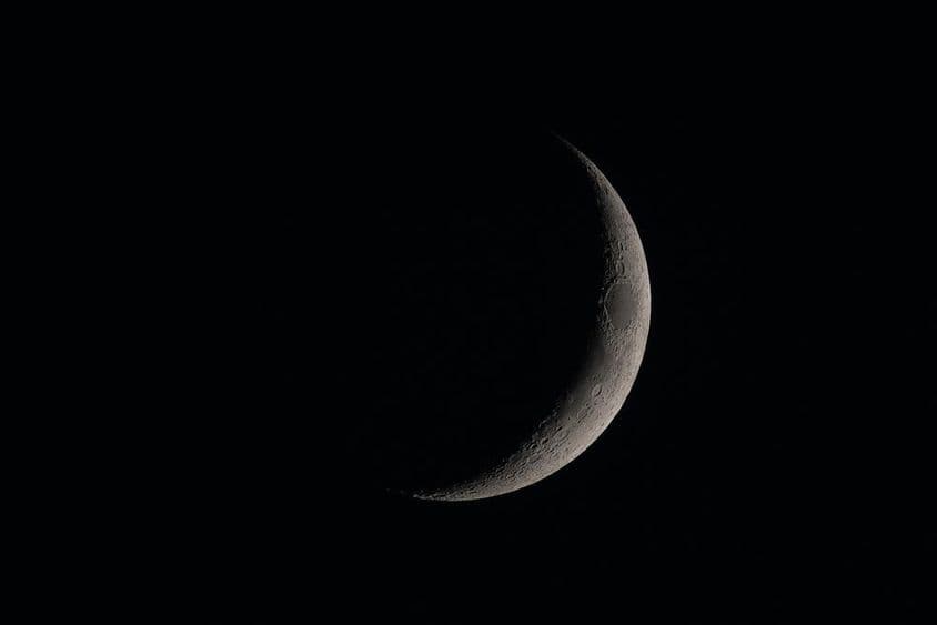 अंधेरे आकाश में विस्तृत नया चंद्रमा।