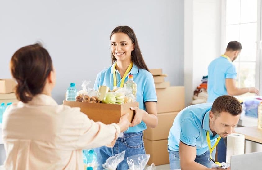 एक युवा स्वयंसेवक जरूरतमंदों को चैरिटी फाउंडेशन पर मुफ्त खाने का डिब्बा देते हुए।