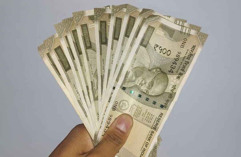भारतीय रुपये के 500 के बैंकनोट पकड़े हुए।