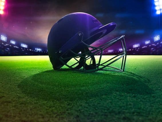 हरे घास पर नीच से क्रिकेट हेलमेट।