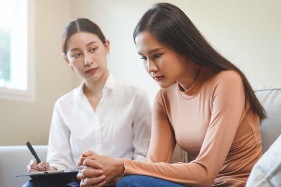 मनोवैज्ञानिक के साथ परामर्श करती दुखी एशियाई युवा महिला