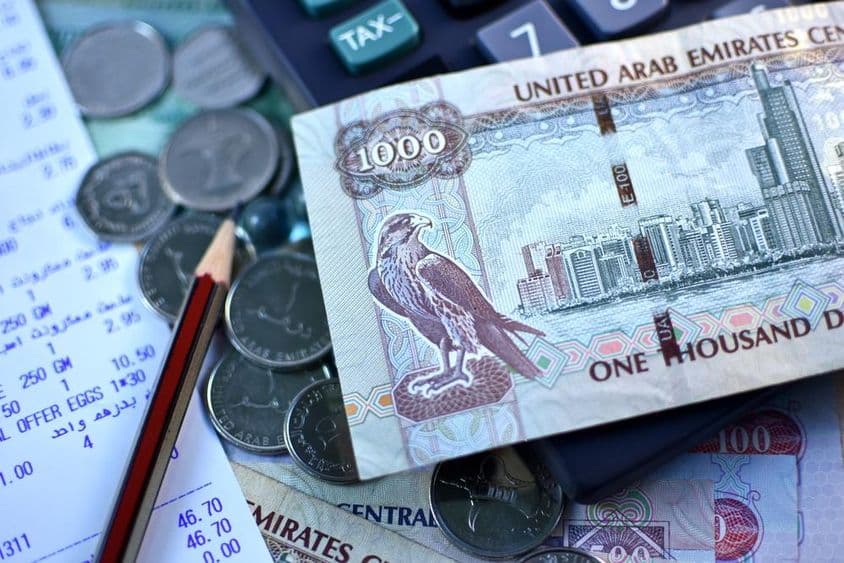 यूएई १००० दिरहम का नोट और कुछ सिक्के।