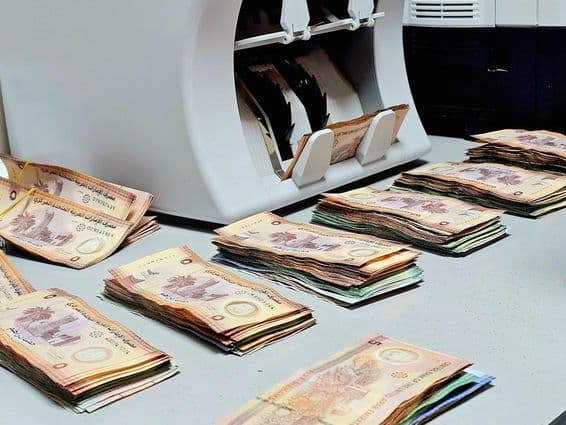 मुद्रा काउंटर मशीन के साथ इमिराती दिरहम नोट एक मेज पर व्यवस्थित