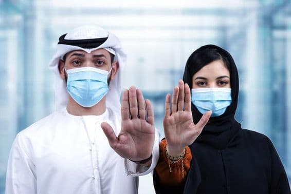मेडिकल मास्क पहने अरबी पुरुष और महिला स्टॉप इशारा करते हुए।