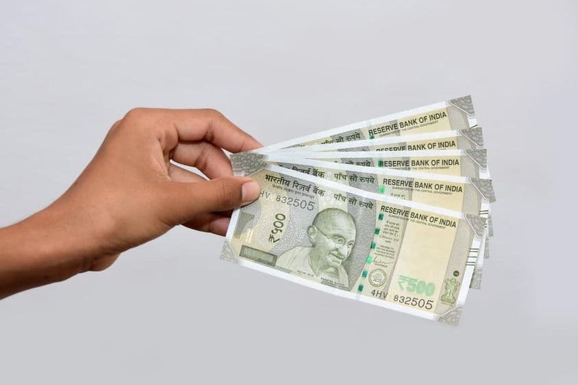 एक व्यक्ति हाथ में नई भारतीय ५०० रुपये की मुद्रा नोट पकड़े हुए।