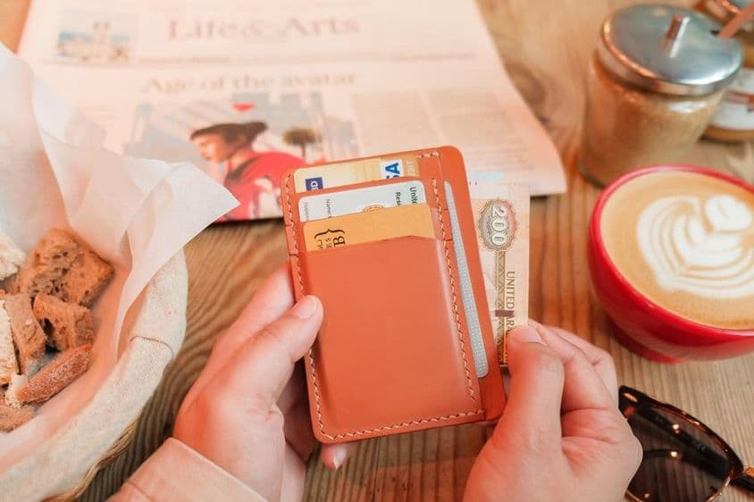 भूरे रंग की चमड़े की कार्डधारक जिसमें आईडी कार्ड, बैंक कार्ड और क्रेडिट कार्ड हैं।