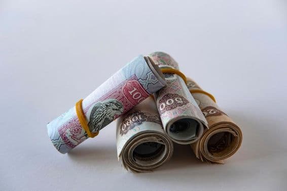 यूएई दिरहम मुद्रा और सिक्कों का एक संग्रह रोल किया हुआ और ढेर किया हुआ।