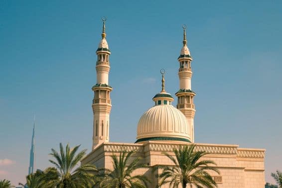 धूप में ताड़ के पेड़ों से घिरी जुमेराह मस्जिद, दुबई।