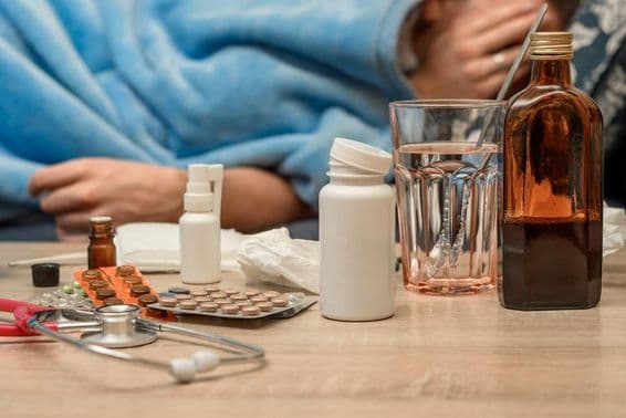 बिस्तर में ठंड और बुखार के साथ एक व्यक्ति।