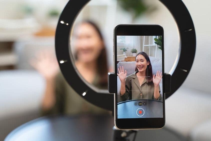 एशियाई युवा महिला अपने चैनल पर ऑनलाइन प्लेटफॉर्म पर प्रसारण करती हुई।