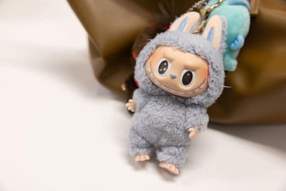 एक महिला के बैग पर प्रसिद्ध पॉपमार्ट लैबूबू का दृश्य।