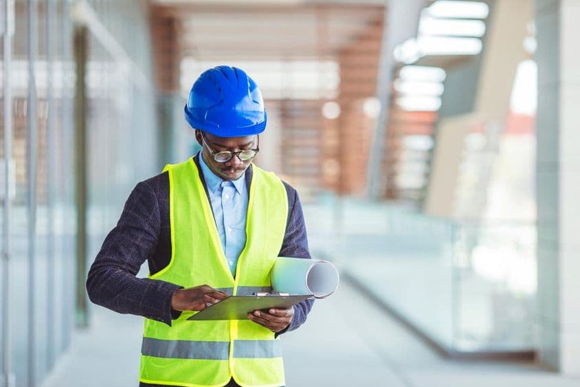 युवा सिविल इंजीनियर कागज के आंकड़ों का विश्लेषण कर रहा है।