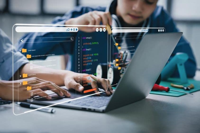 रोबोटिक आर्म्स और रोबोट कारों से संबंधित होमवर्क कर रहे एशियाई किशोर छात्र।