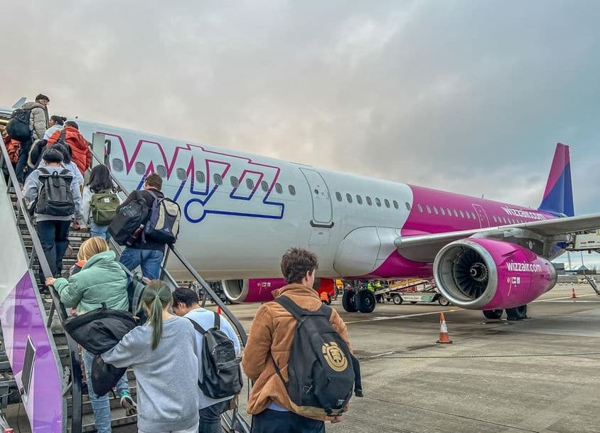 Wizz Air एयरलाइन विमान में चढ़ते बैकपैकर