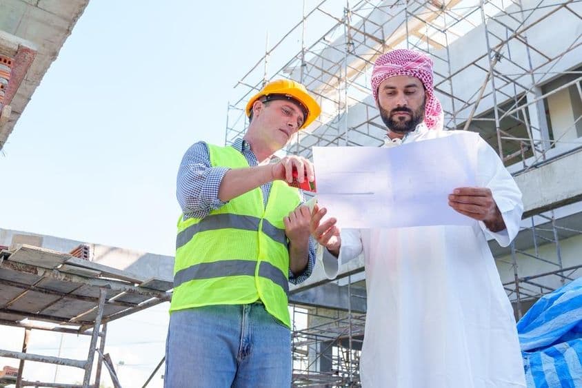 अरबी व्यापारी एक सिविल इंजीनियरिंग ब्लूप्रिंट की जाँच करते हुए।