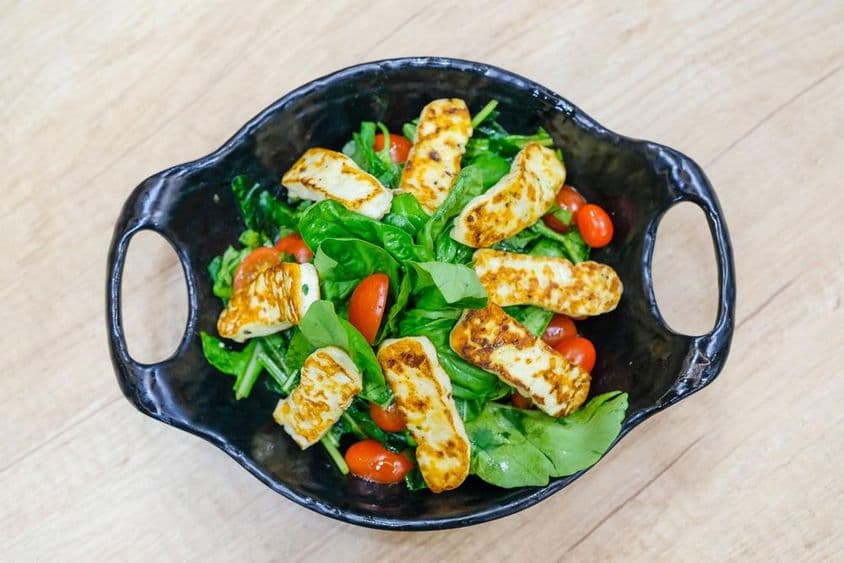 अरुगुला पत्तियों और चेरी टमाटरों के साथ चीज सलाद।